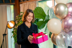 profesora recibiendo un regalo de sus alumnos en una caja rosa